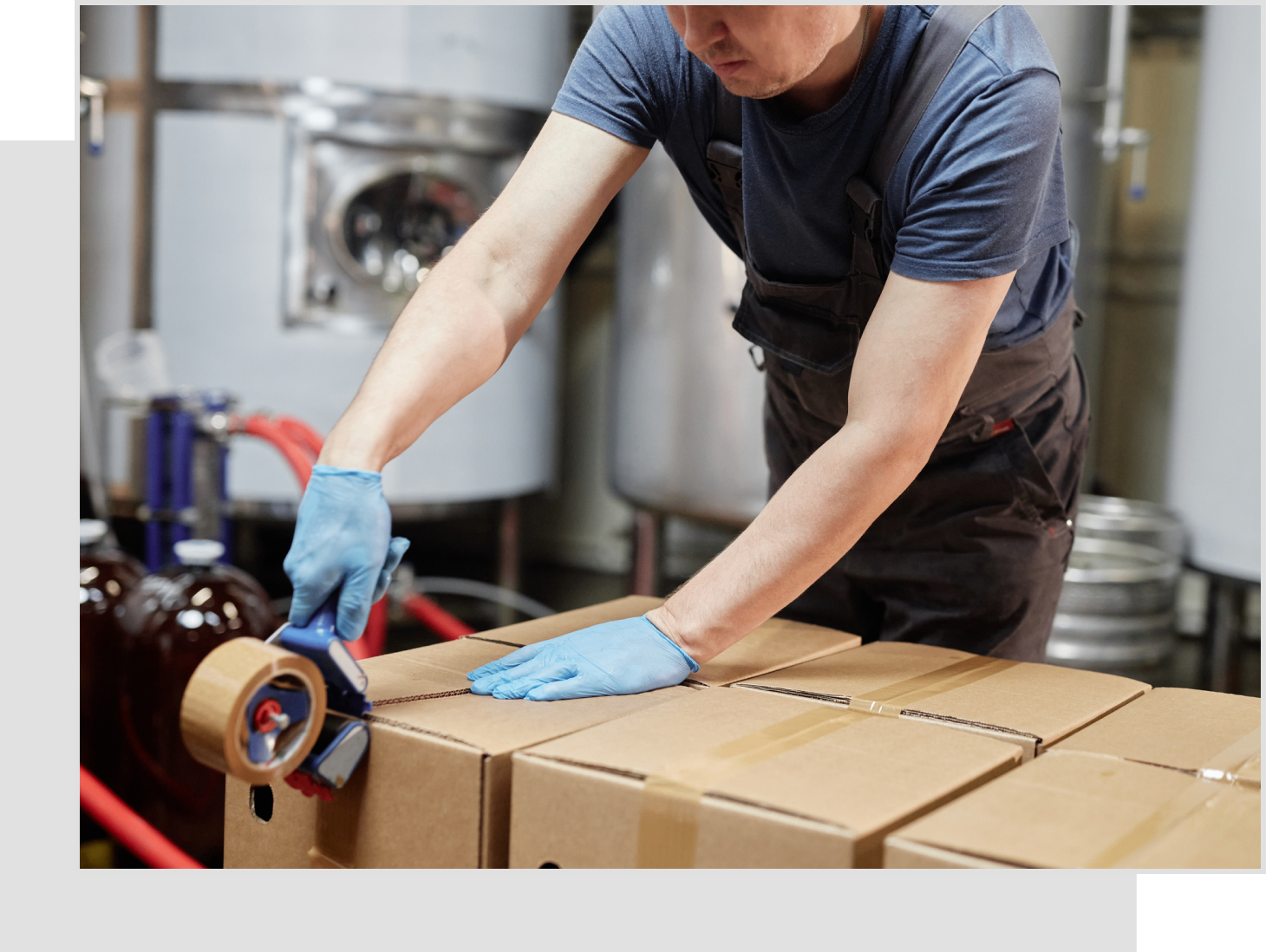 A man in blue gloves taping boxes with tape.